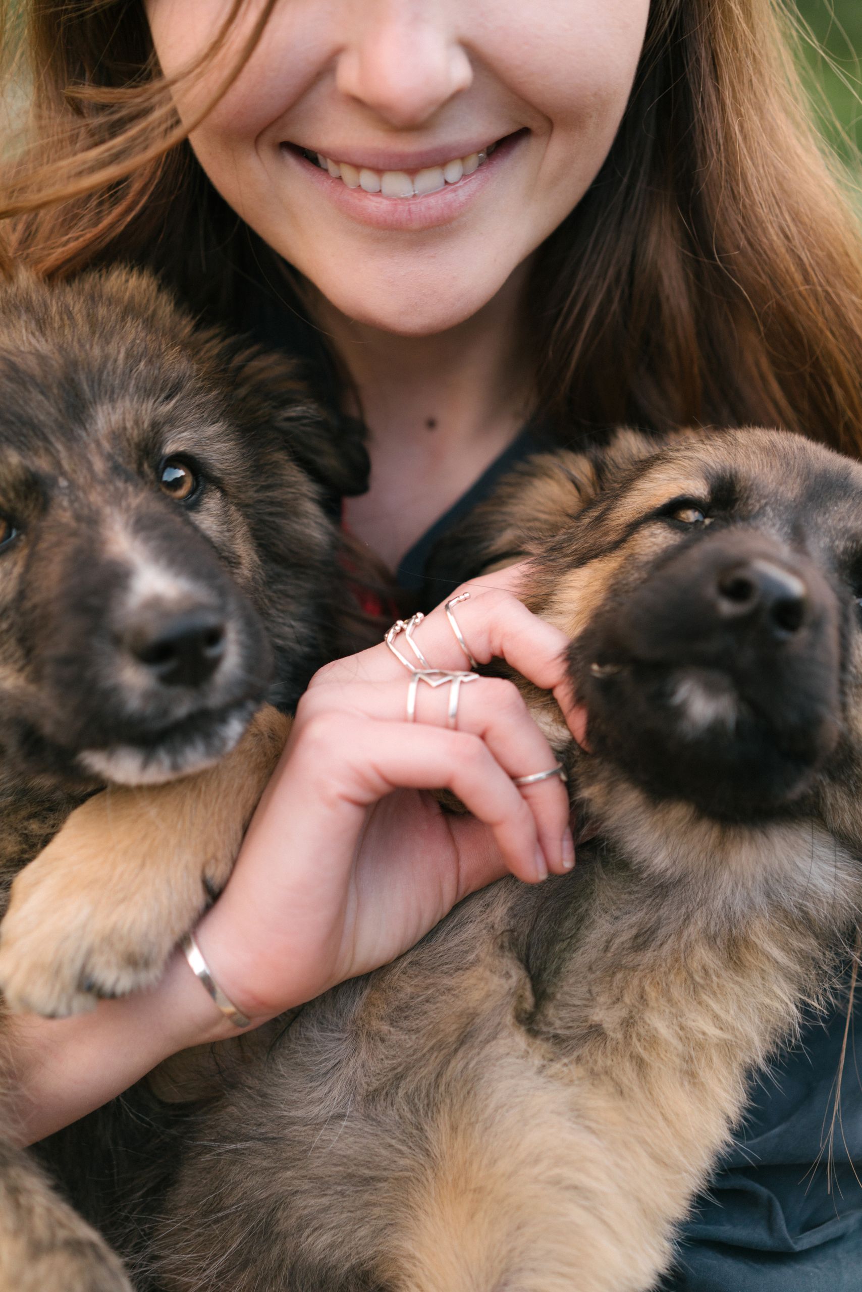 A joyful woman embraces two adorable German Shepherd puppies, showcasing love and companionship.